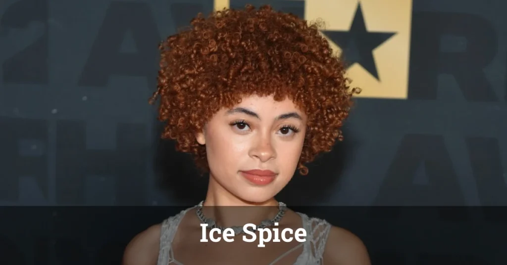 Ice Spice performing live on stage, wearing a stylish outfit and engaging with an excited audience.