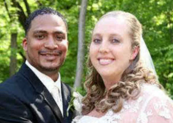 Corrie Bird on her wedding day with husband Trent Batson in formal attire against a green natural background