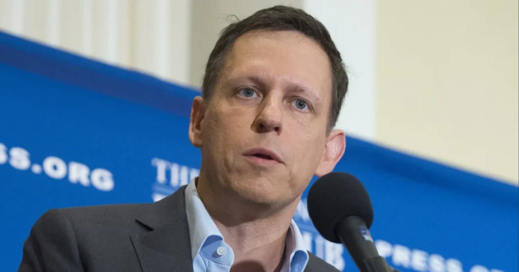 Matt Danzeisen speaking at a professional event with a microphone in front of him and a blue backdrop featuring an organization logo.