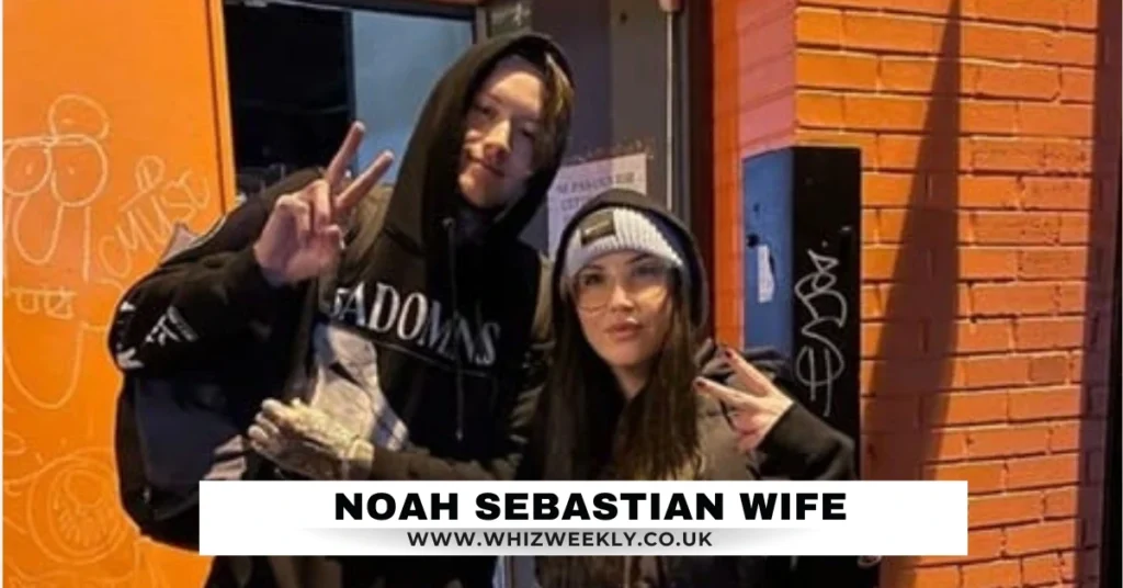 Noah Sebastian Wife, both dressed in stylish streetwear, showing peace signs outside a vibrant urban venue.
