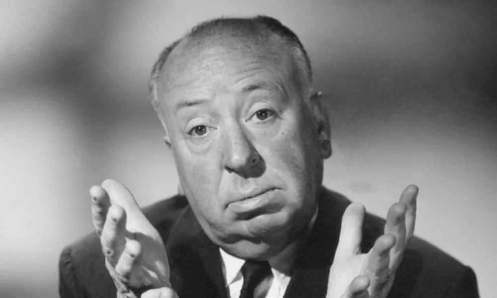 Alfred Hitchcock Net Worth: The Master of Suspense gesturing dramatically in his iconic pose that helped build his $200 million fortune
