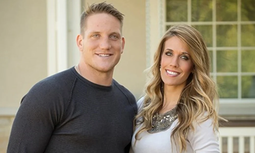 AJ Hawk standing with his wife outside their home, representing AJ Hawk Net Worth and his successful post-NFL lifestyle.