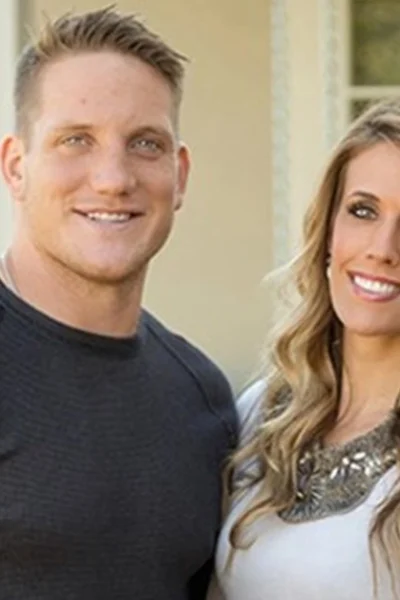 AJ Hawk standing with his wife outside their home, representing AJ Hawk Net Worth and his successful post-NFL lifestyle.