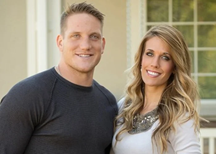 AJ Hawk standing with his wife outside their home, representing AJ Hawk Net Worth and his successful post-NFL lifestyle.