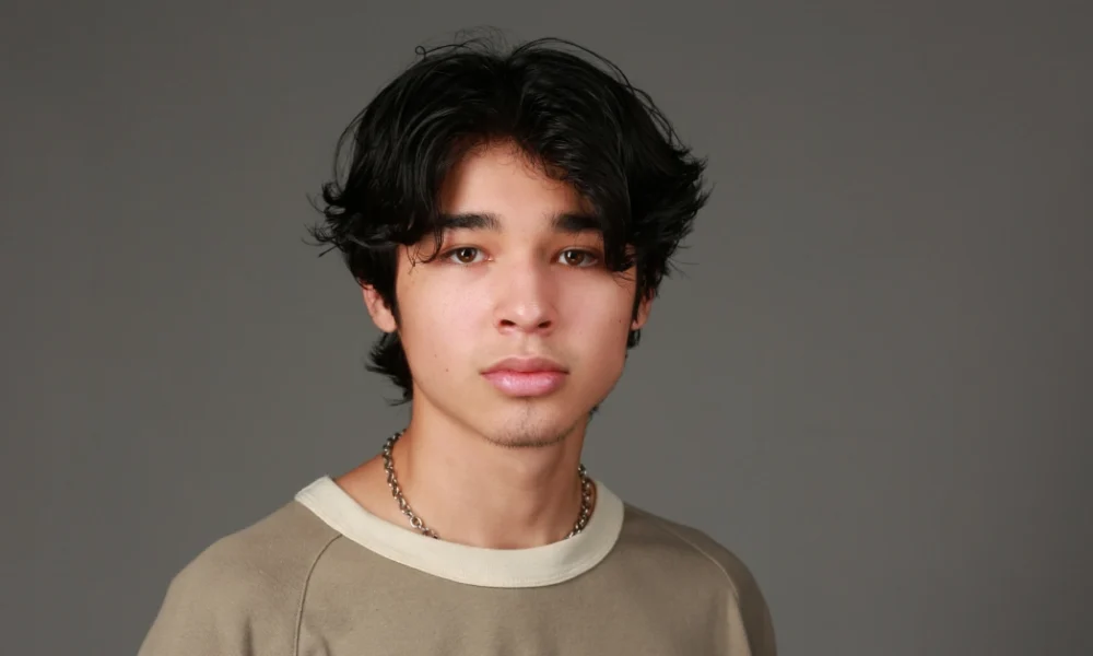 Isaac Arellanes: Inside His Breakthrough Hollywood Journey in 2025 Isaac Arellanes in a beige shirt and chain necklace, embodying his unique style and presence as a prominent young Hollywood actor.
