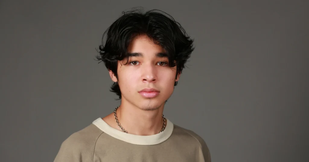 Isaac Arellanes in a beige shirt and chain necklace, embodying his unique style and presence as a prominent young Hollywood actor.