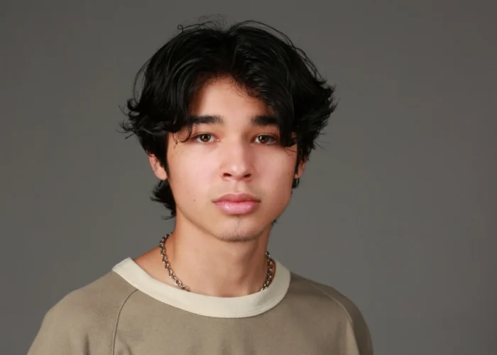 Isaac Arellanes in a beige shirt and chain necklace, embodying his unique style and presence as a prominent young Hollywood actor.
