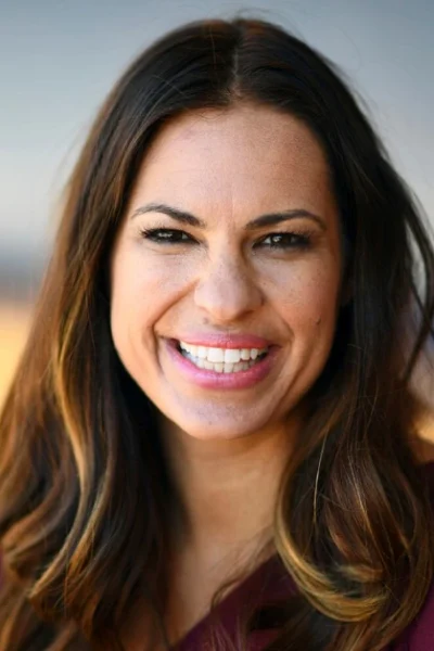 Jessica Mendoza smiling confidently in purple attire, representing her transition from Olympic softball champion to pioneering ESPN baseball analyst breaking gender barriers.